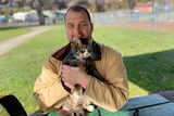 A man holds a tabby cat and smiles