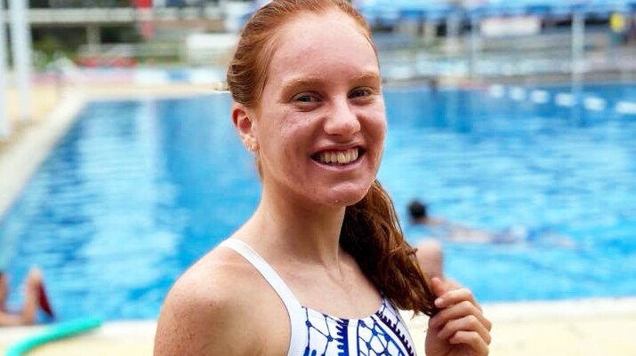 Young red-headed woman wearing a swimsuit looks to the camera.