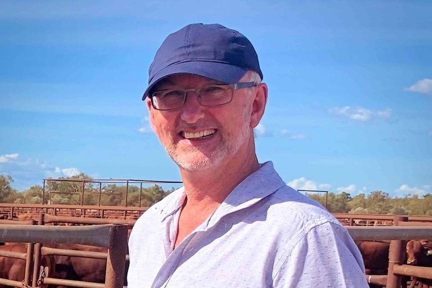 A smiling man wears a blue cap in the sunshine