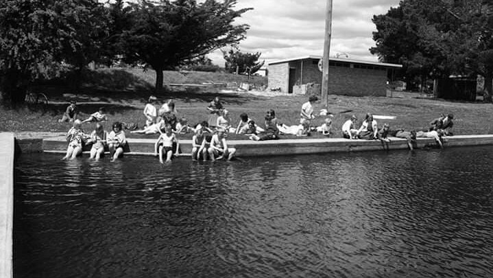 Black and white photo of people swimming in a river