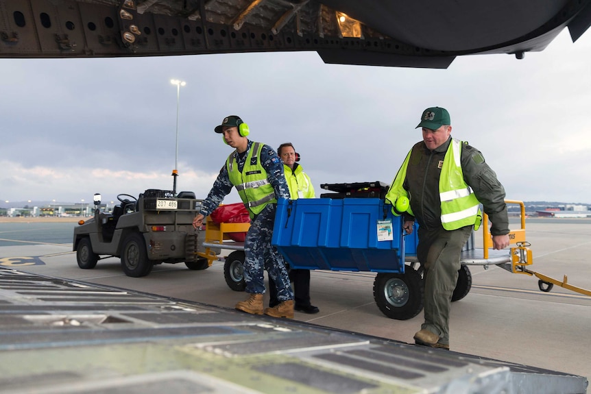 Rescuers load specialist equipment on to a C-17A Globemaster aircraft at Canberra Airport.