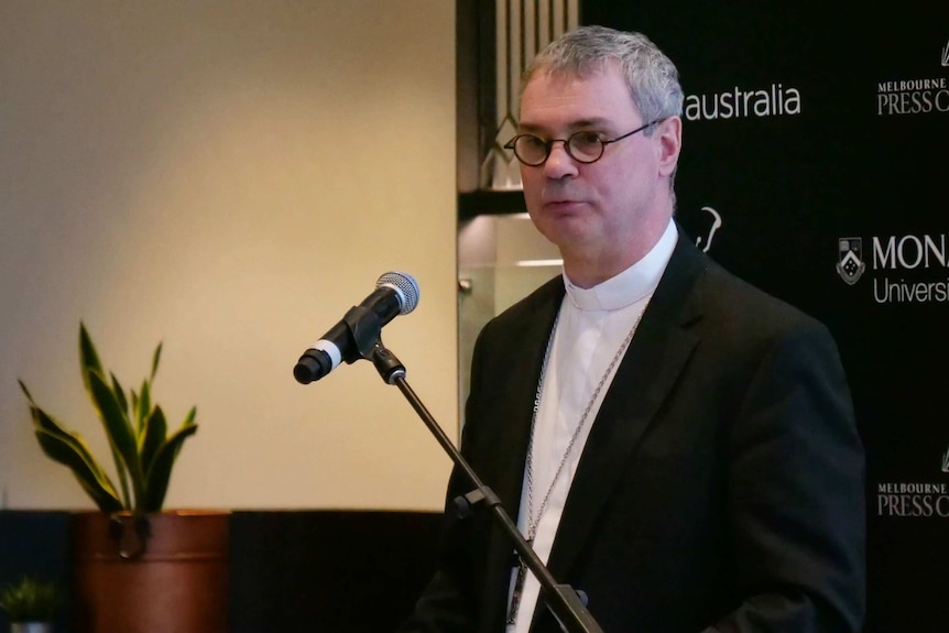 Melbourne Archbishop Peter Comensoli standing at a lectern and microphone.