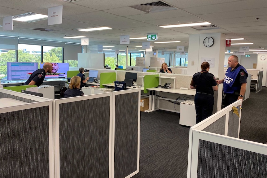 An office with people in emergency service uniforms and TVs