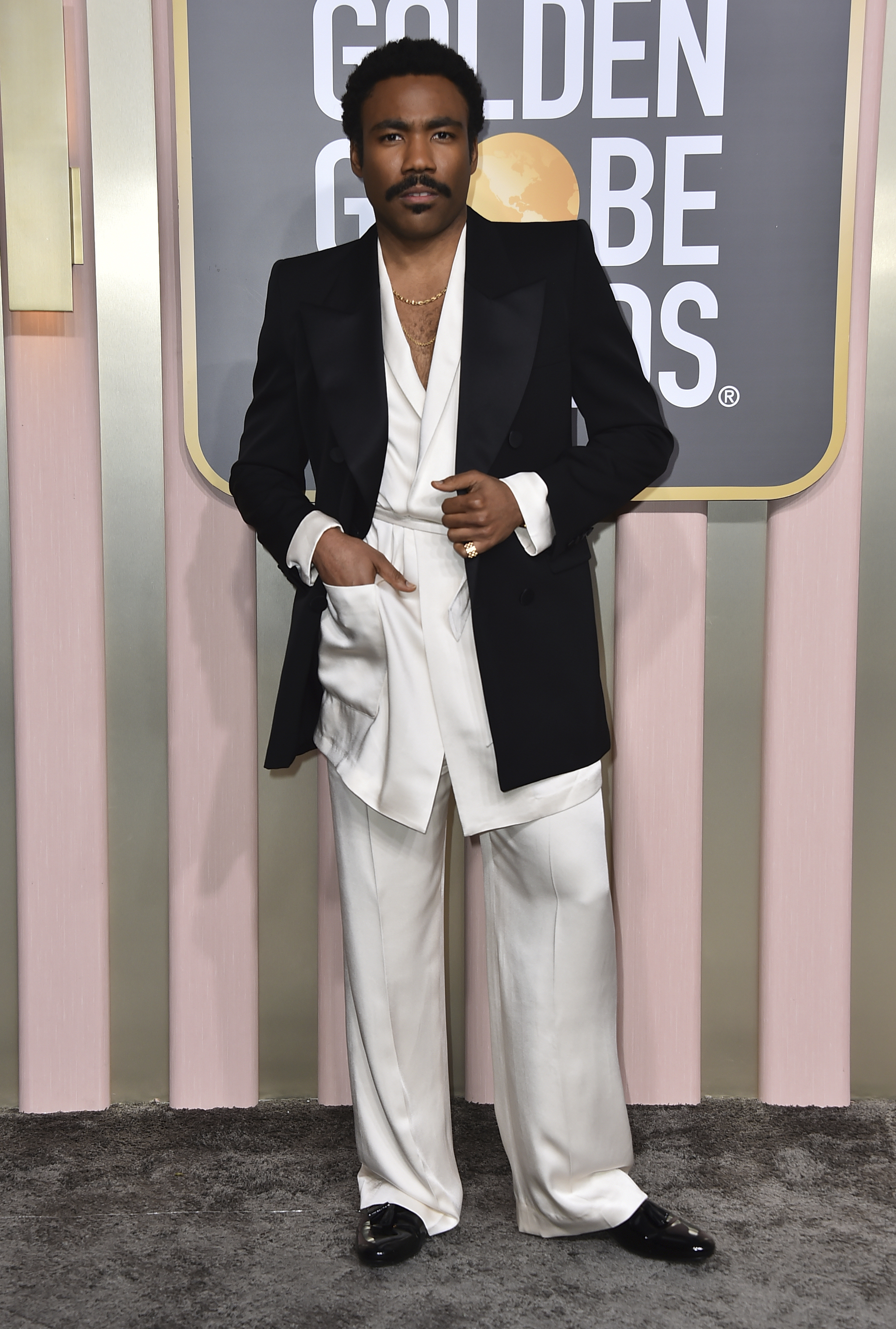 Donald Glover wearing a silky white suit with a black jacket.
