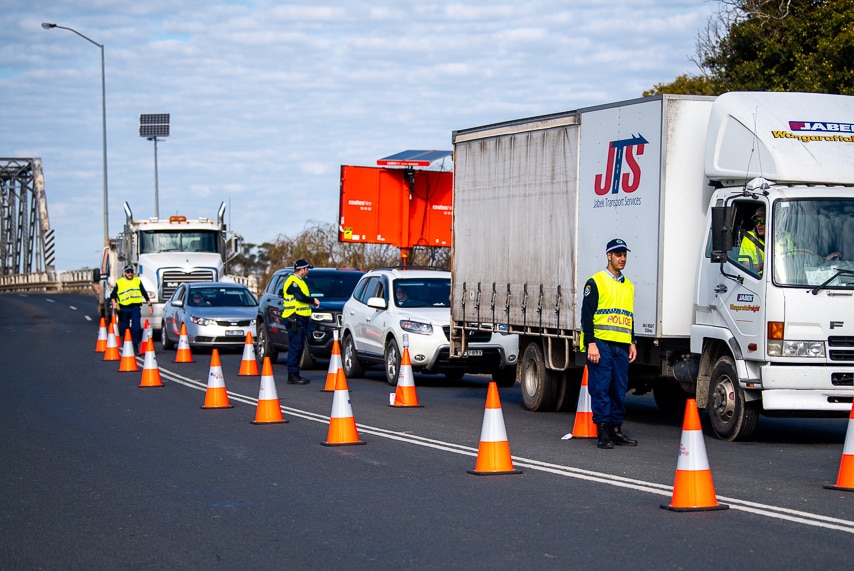 trucks and a cars in a queue after a bridge