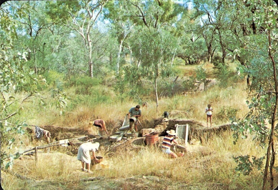 A landscape shot of men, women and children sifting through dirt