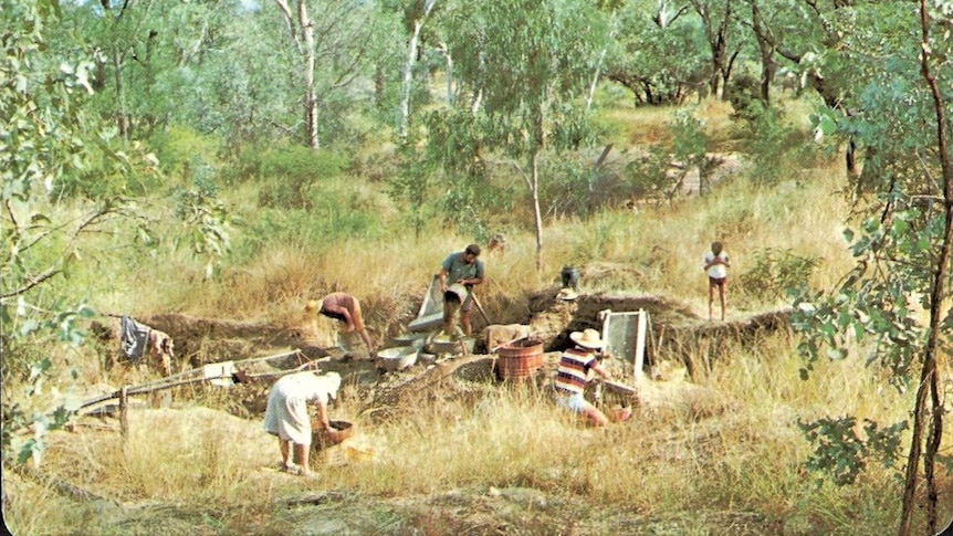 A landscape shot of men, women and children sifting through dirt