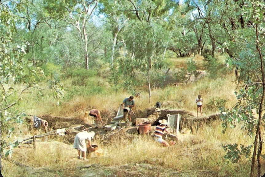 A landscape shot of men, women and children sifting through dirt