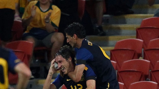 Staking his claim...Mark Milligan (bottom) scored his first international goal to take the win for Australia.