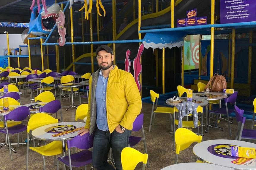 A man stands in the cafe area of a kids playground. 