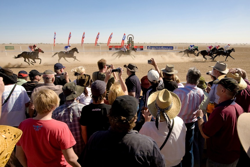 A crowd at a dusty horse race.
