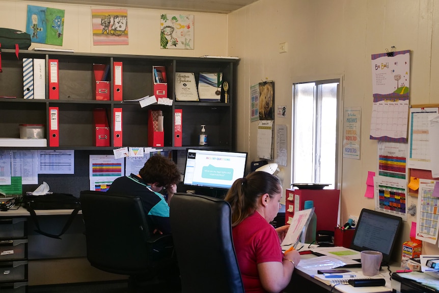 Campbell West studying at his desk while his tutor Bianca Sanders sits to the right of him