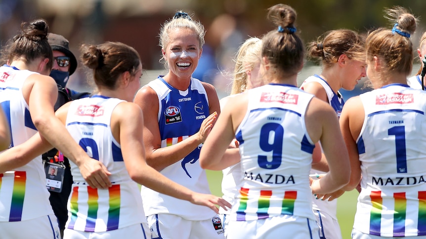 North Melbourne in a huddle smiling after defeating GWS Giants in the AFLW 