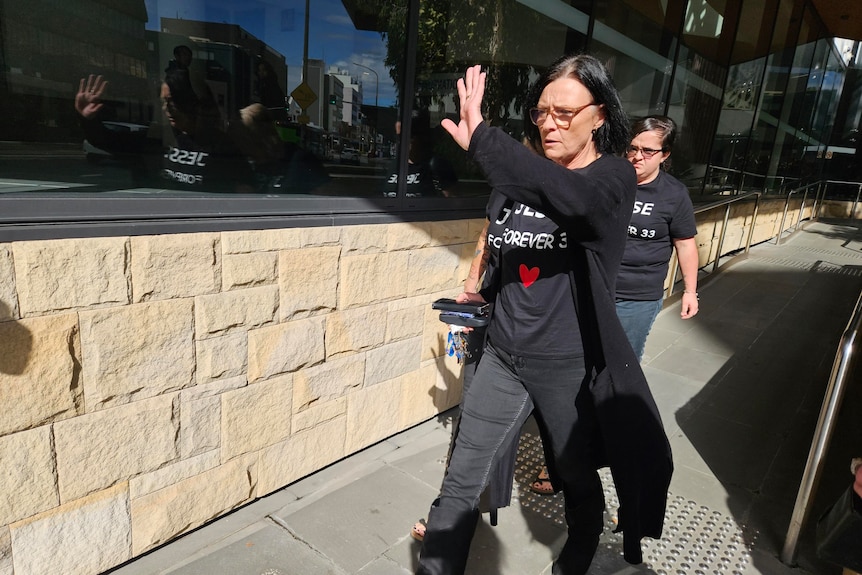 A with a shirt saying 'Jesse Forever 33' walks out of a court with her hand up with two others wearing similar shirts trail her