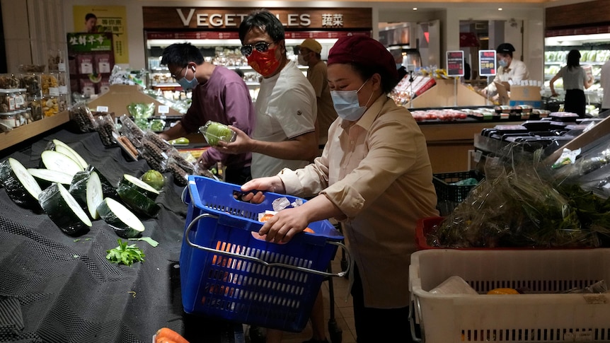 Shoppers look through bare vegetable shelves at a Beijing supermarket.