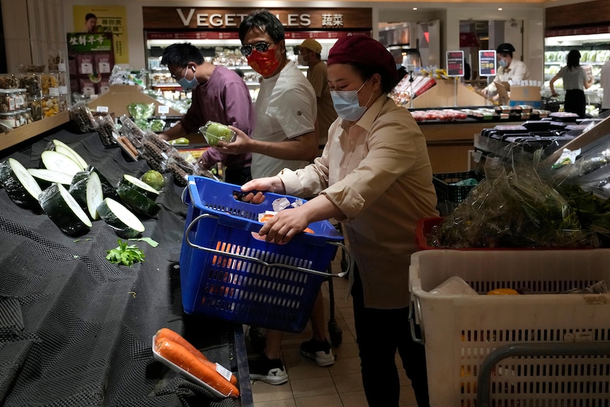 Kupujący przeglądają półki pełne nagich warzyw w supermarkecie w Pekinie.