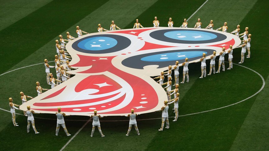 Performers hold World Cup logo on pitch at opening ceremony