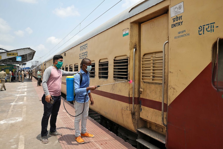 A man disinfects a door of a train in India.