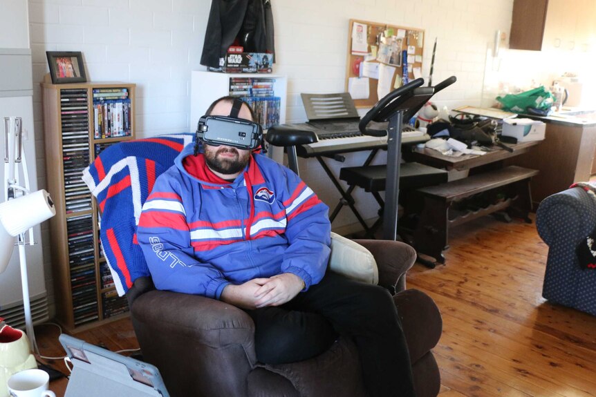 man sits on arm chair in bulldogs jumper with VR device over his eyes