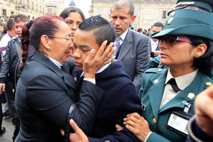 Johan Steven is embraced by a relative during his father's funeral in Bogota, Colombia.