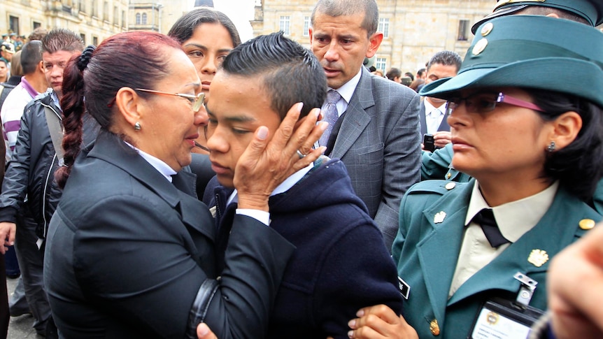 Johan Steven is embraced by a relative during his father's funeral in Bogota, Colombia.