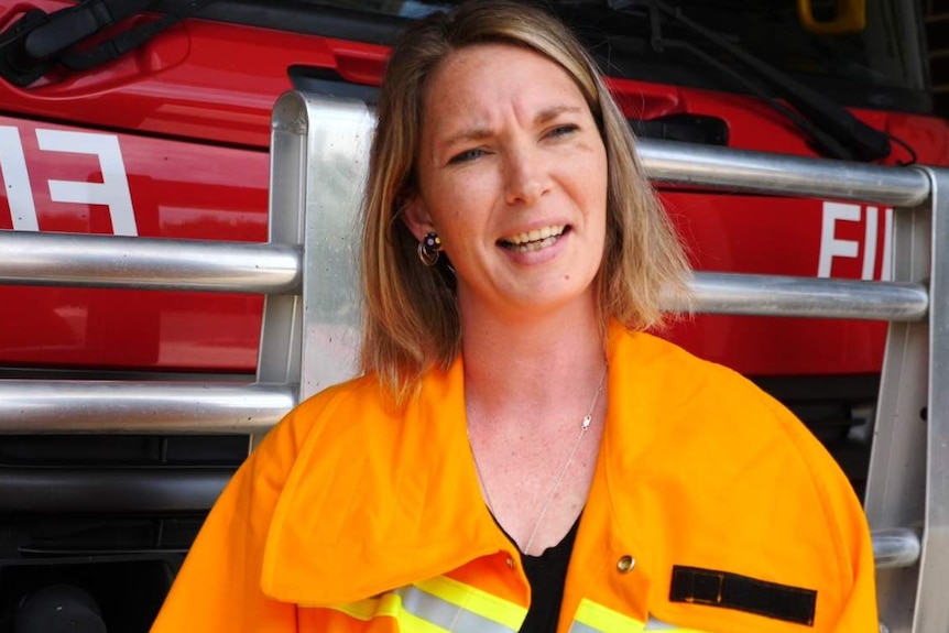 A woman standing in front of a fire truck.