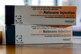 Two white and orange boxes on table with Naloxone Injection written and prescripton only medicine.
