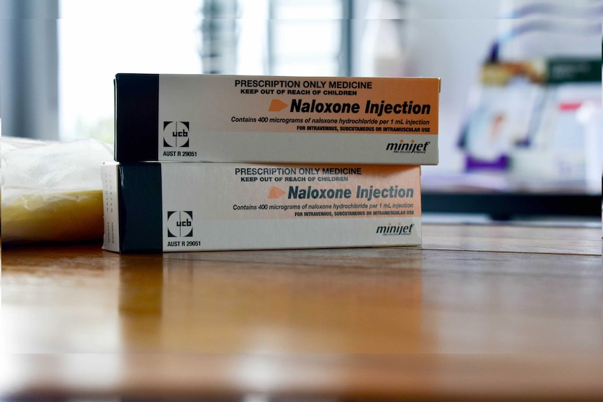 Two boxes of naloxone injectors sit on a table with the rest of the room out of focus