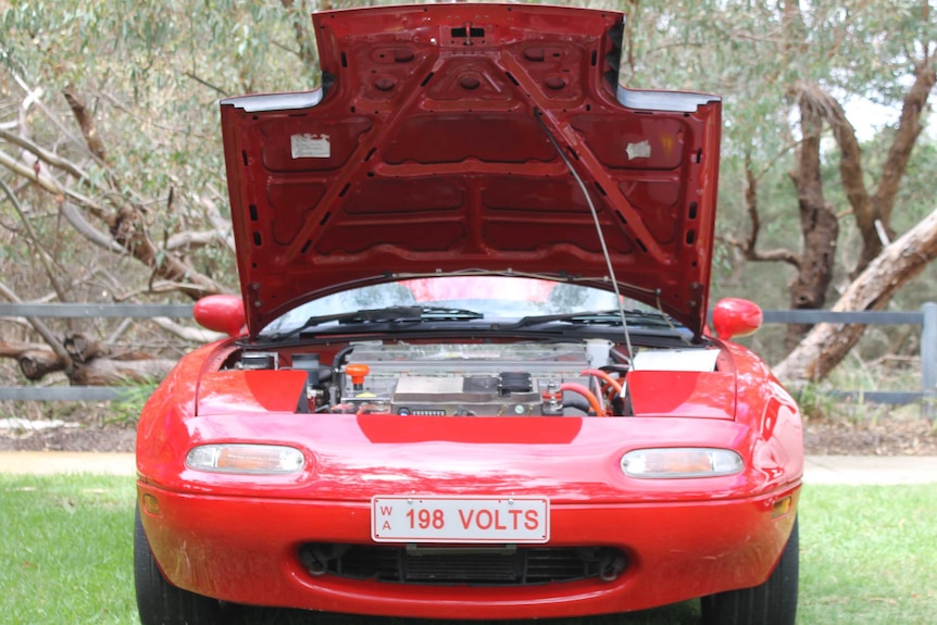 red car with bonnet up and number plate reading 198 Volts