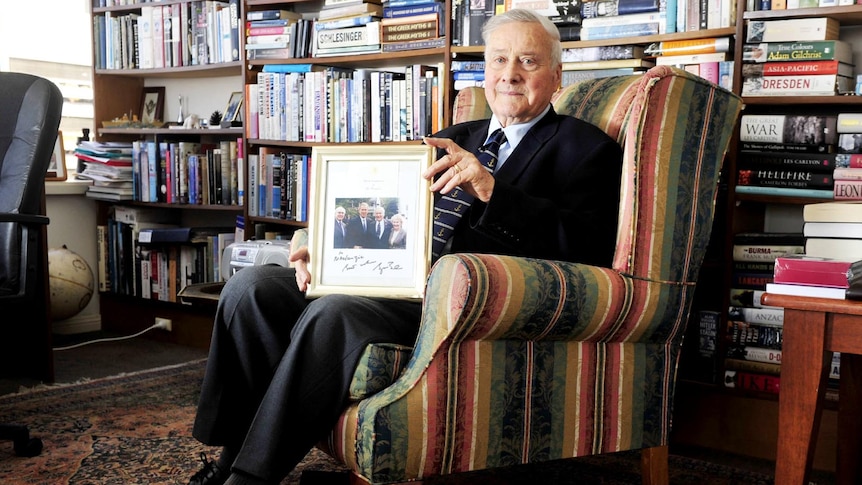 Mackenzie Gregory holds a photo taken on September 10, 2001 of himself with wife Denise, John Howard and George W Bush.