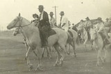 Men and children riding horses in a grand parade. The picture is in black and white