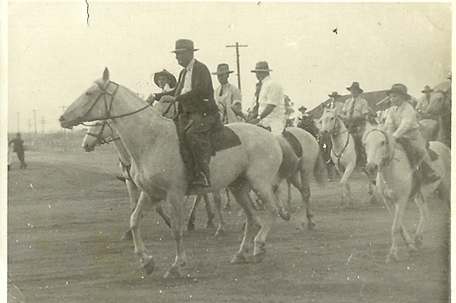 Men and children riding horses in a grand parade. The picture is in black and white