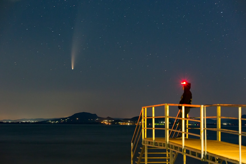 A man watches from a stairwell as Comet Neowise is seen in the morning sky above Balatonmariafurdo in Hungary