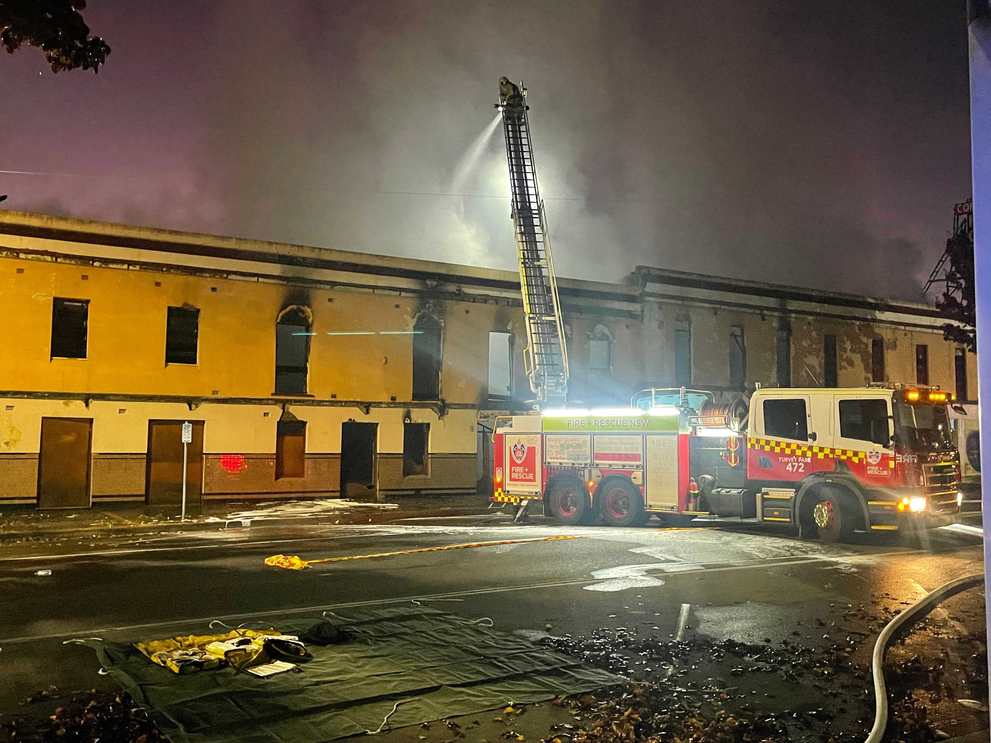 A fire engine blasting water onto a burning building with smoke all around. 