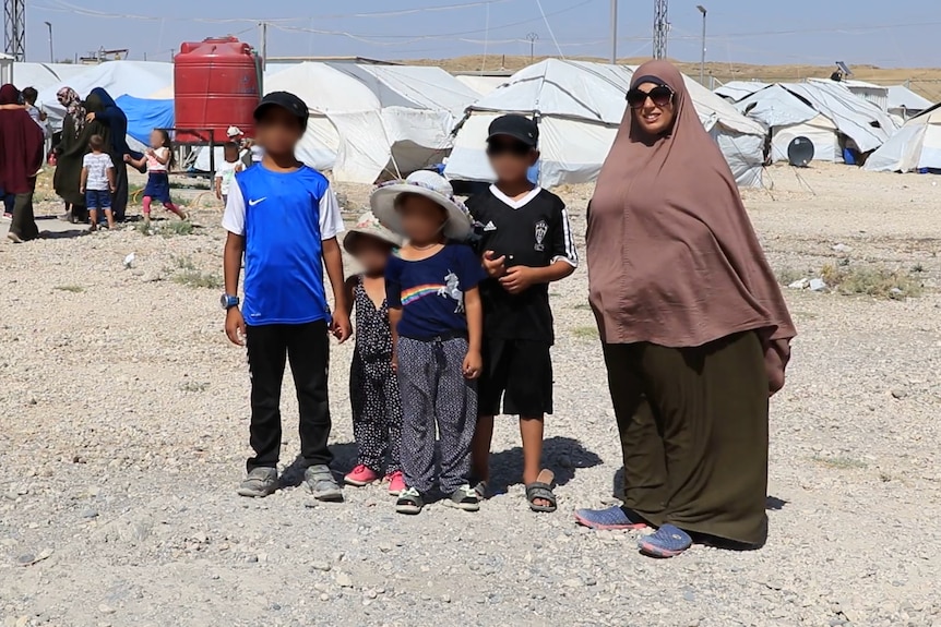 Four children stand next to a woman.