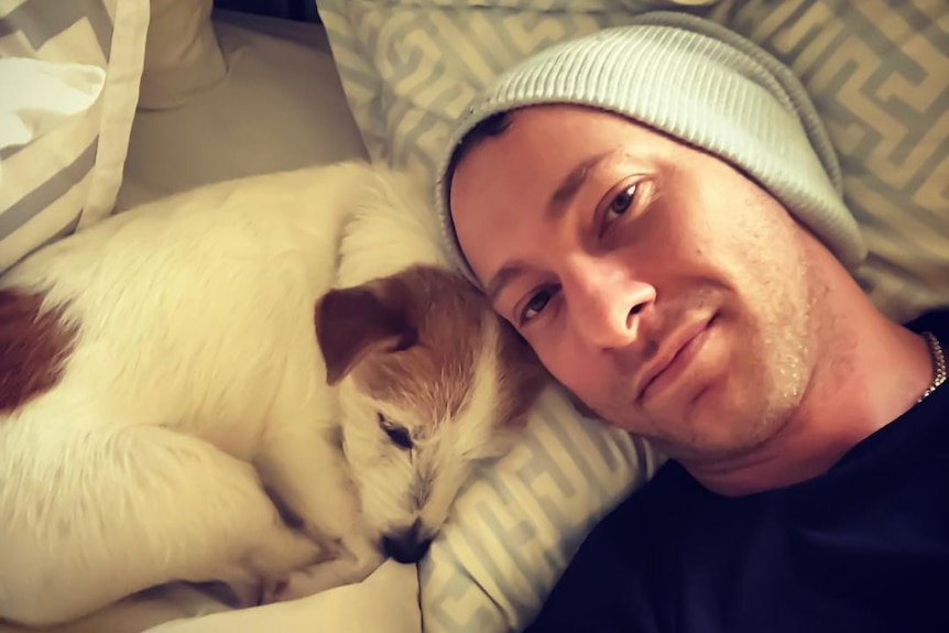 Chris Stanmore wearing a hat while posing with a white dog