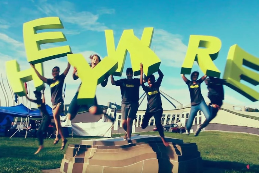 young people jumping with a heywire sign