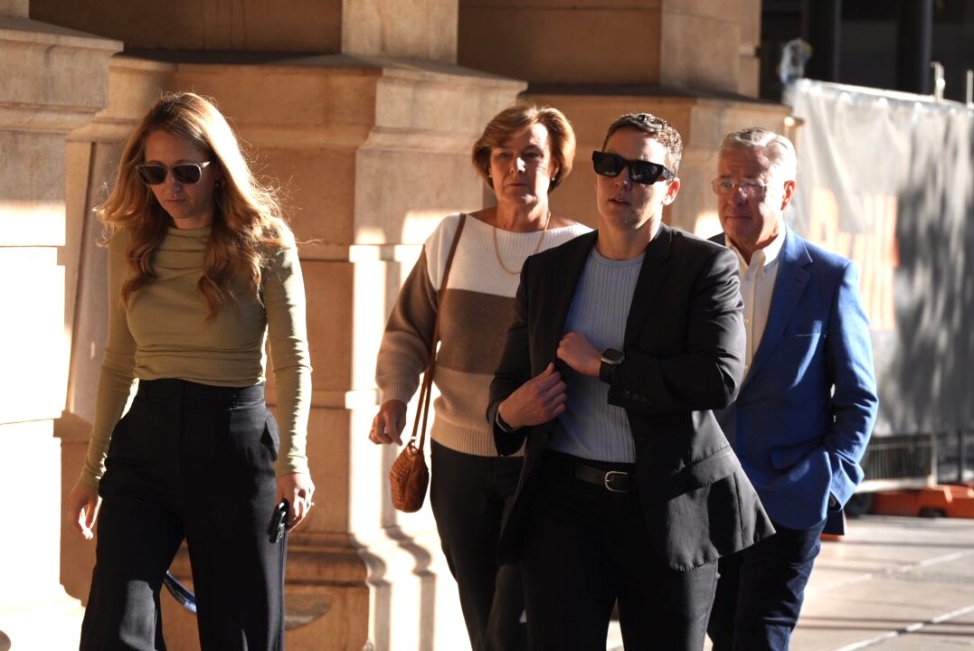 Two women and two men walk in a group next to a court building