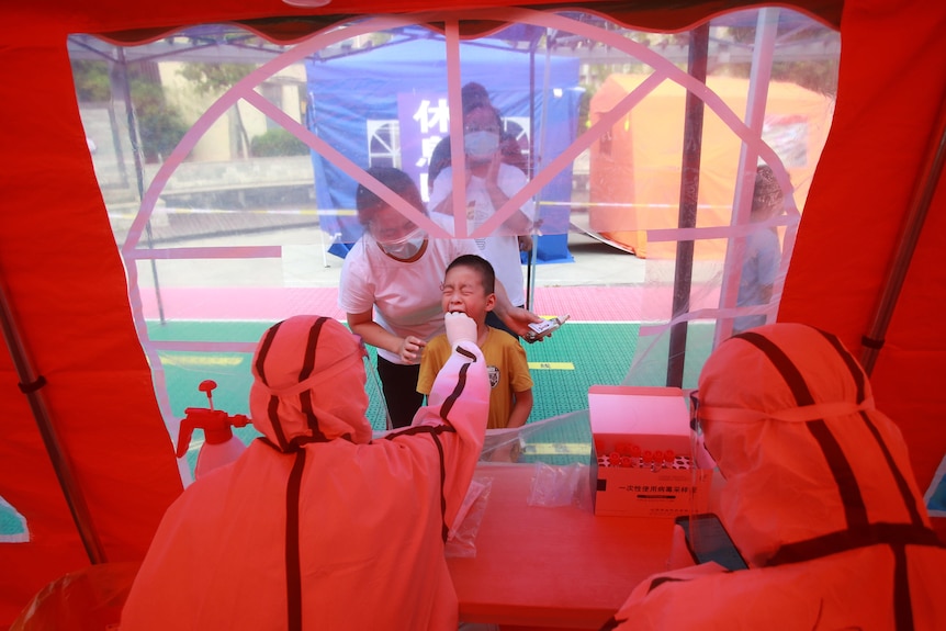 在中国扬州，一名儿童在 PPE 的 PPE 中被一名护理人员在嘴里摩擦后抓伤了他的脸