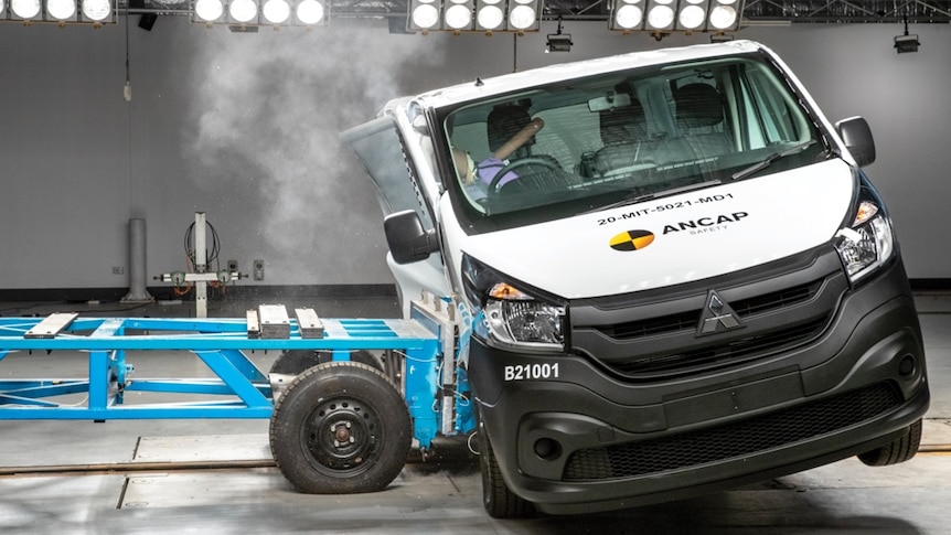 A trolley smashes into the side of a van with a crash test dummy in it.