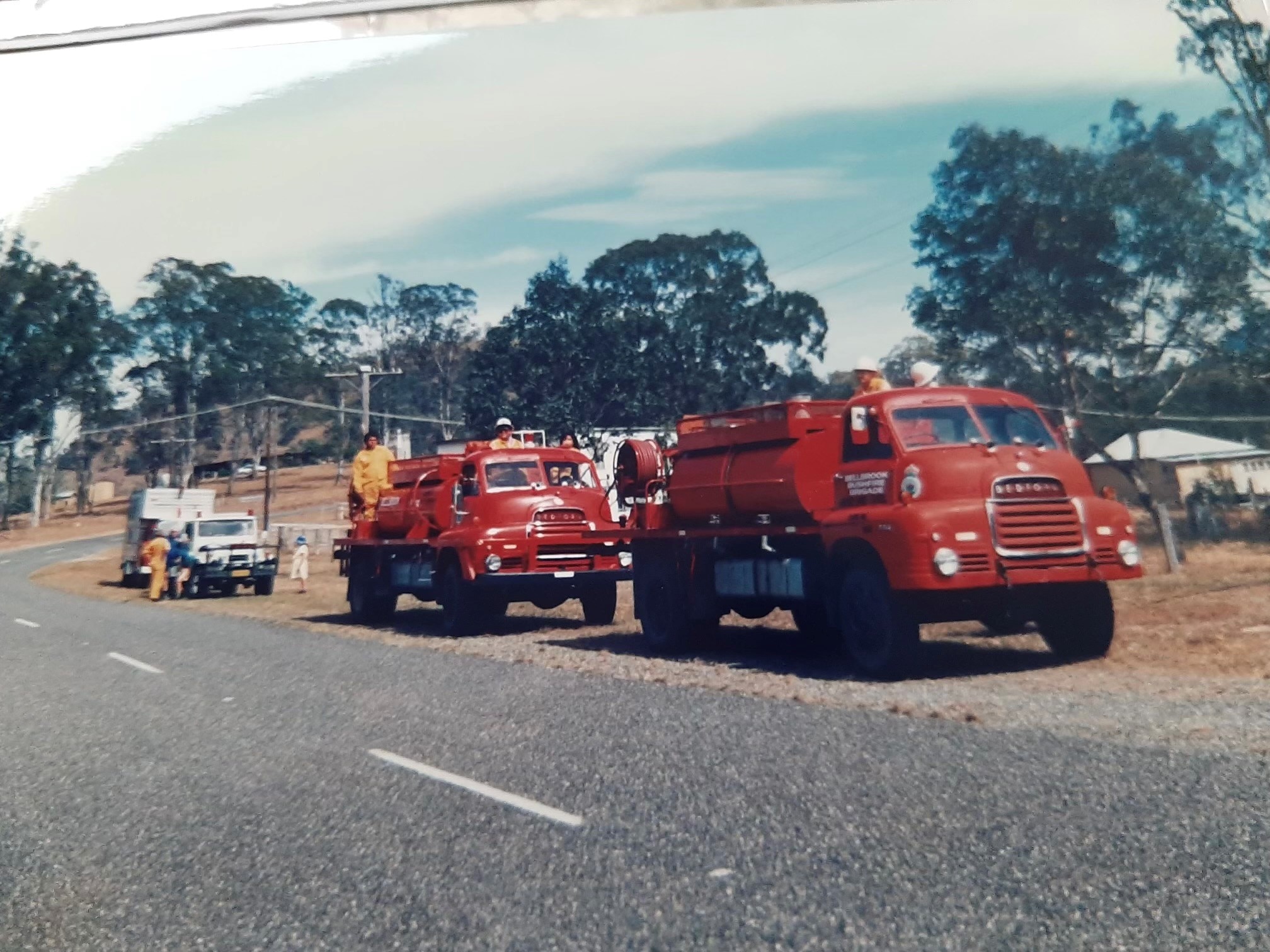Two old red fire trucks on a country road.