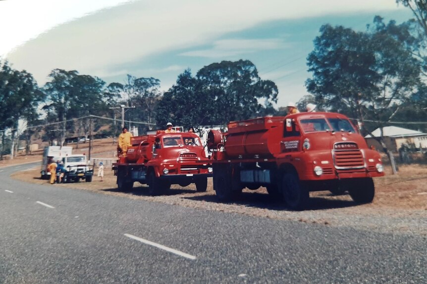 Two old red fire trucks on a country road.