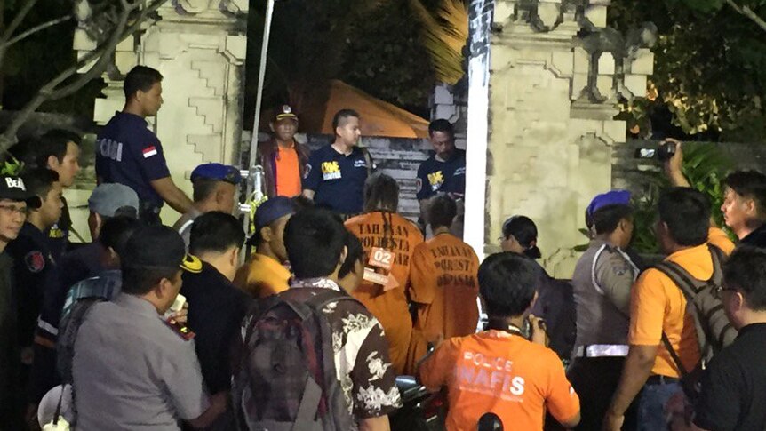 Murder accused Sara Connor and David Taylor, wearing orange jumpsuits, are surrounded by media and police on Kuta beach, Bali.