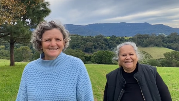 Carla Rogers standing next to Bardi elder Aunty Munya Andrews with green rolling hills in the background