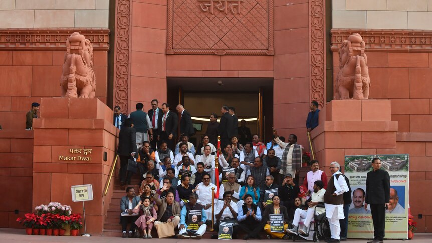 Indian lawmakers pose for a photo on the stairs of the parliament building.
