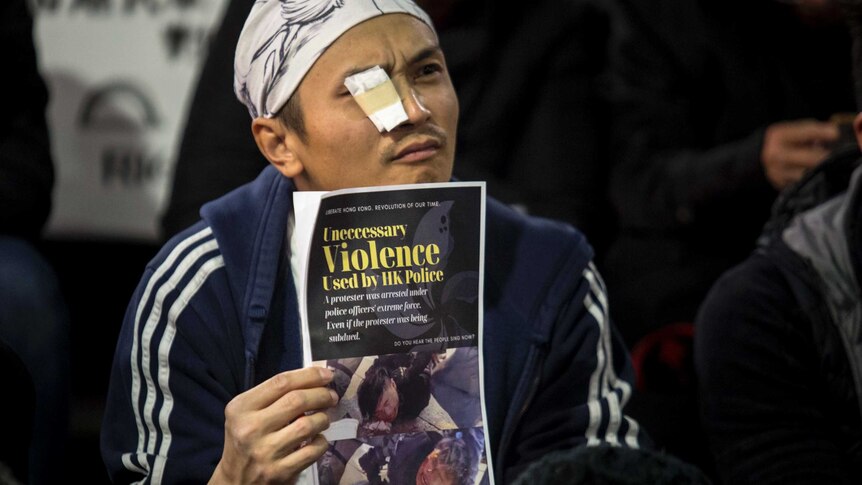 man with bandaid over eye holding a graphic paper
