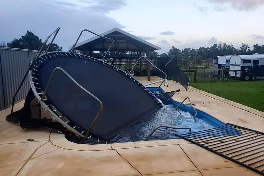A trampoline lies upside down in a swimming pool.