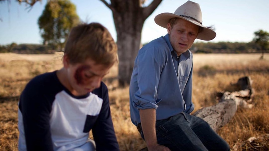 Still image from film Calloused Hearts - two characters sit in a paddock