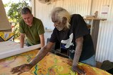 Two men look at a large colourful map