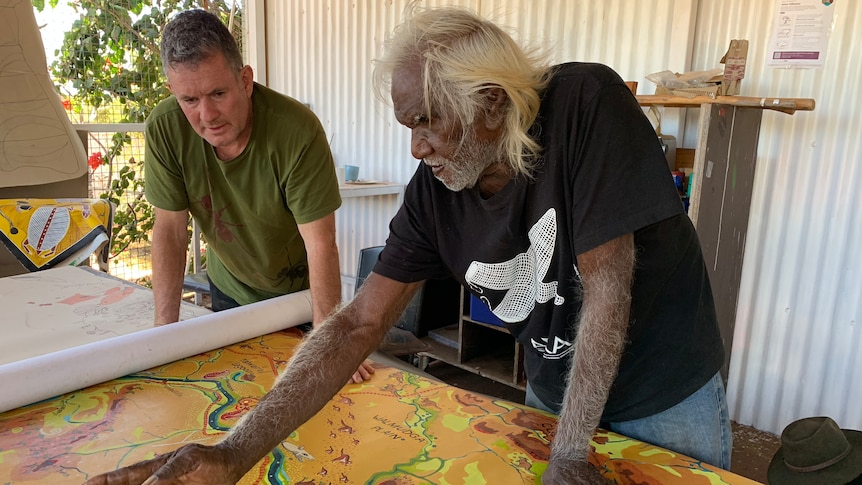 Two men look at a large colourful map